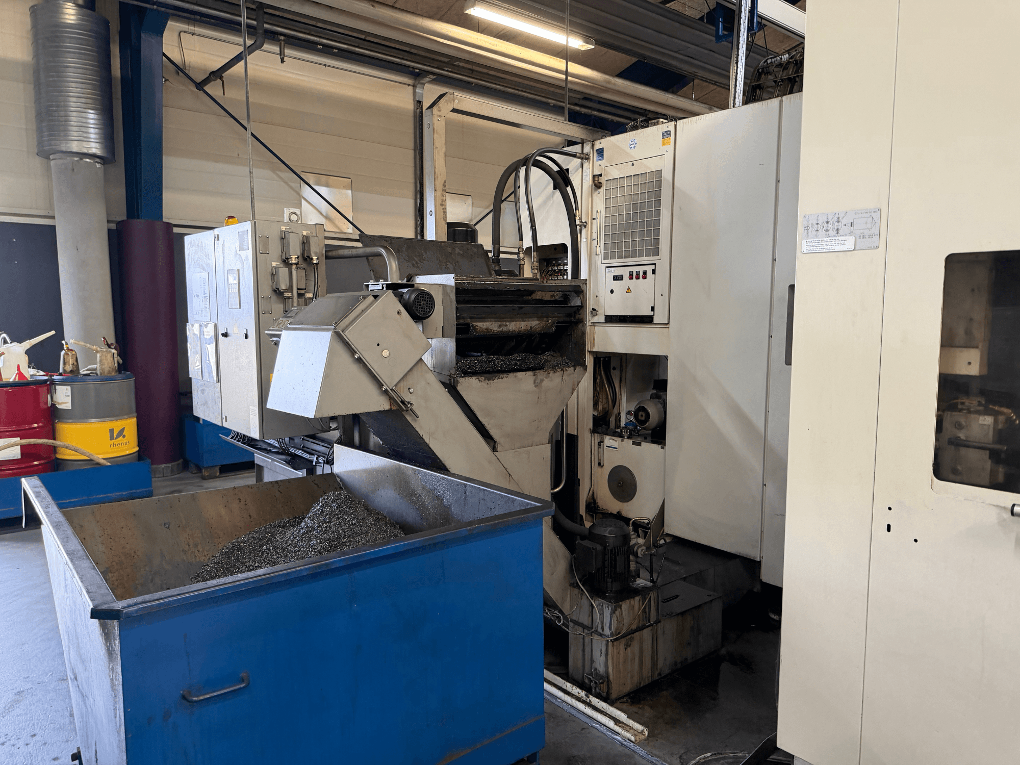 HELLER MCH 250 horisontaaltöötluskeskuse esiplaanil, kus on näha metalli jahutusvedeliku ringlussevõtu mahuti ja juhtpaneel.