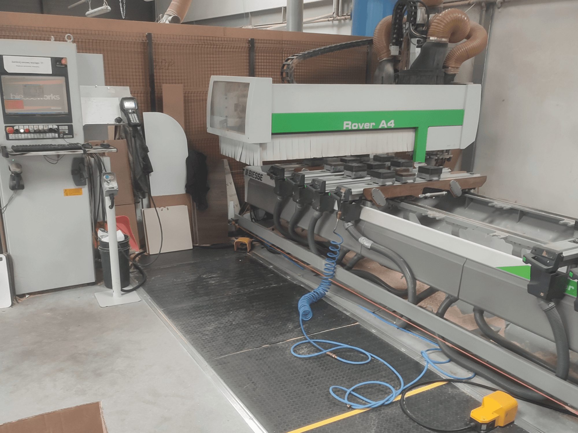 BIESSE Rover A4 CNC-puidutöötluskeskus külgvaates, millel on näha juhtpaneel, vaakumkinnitused ja tolmuärastussüsteem.