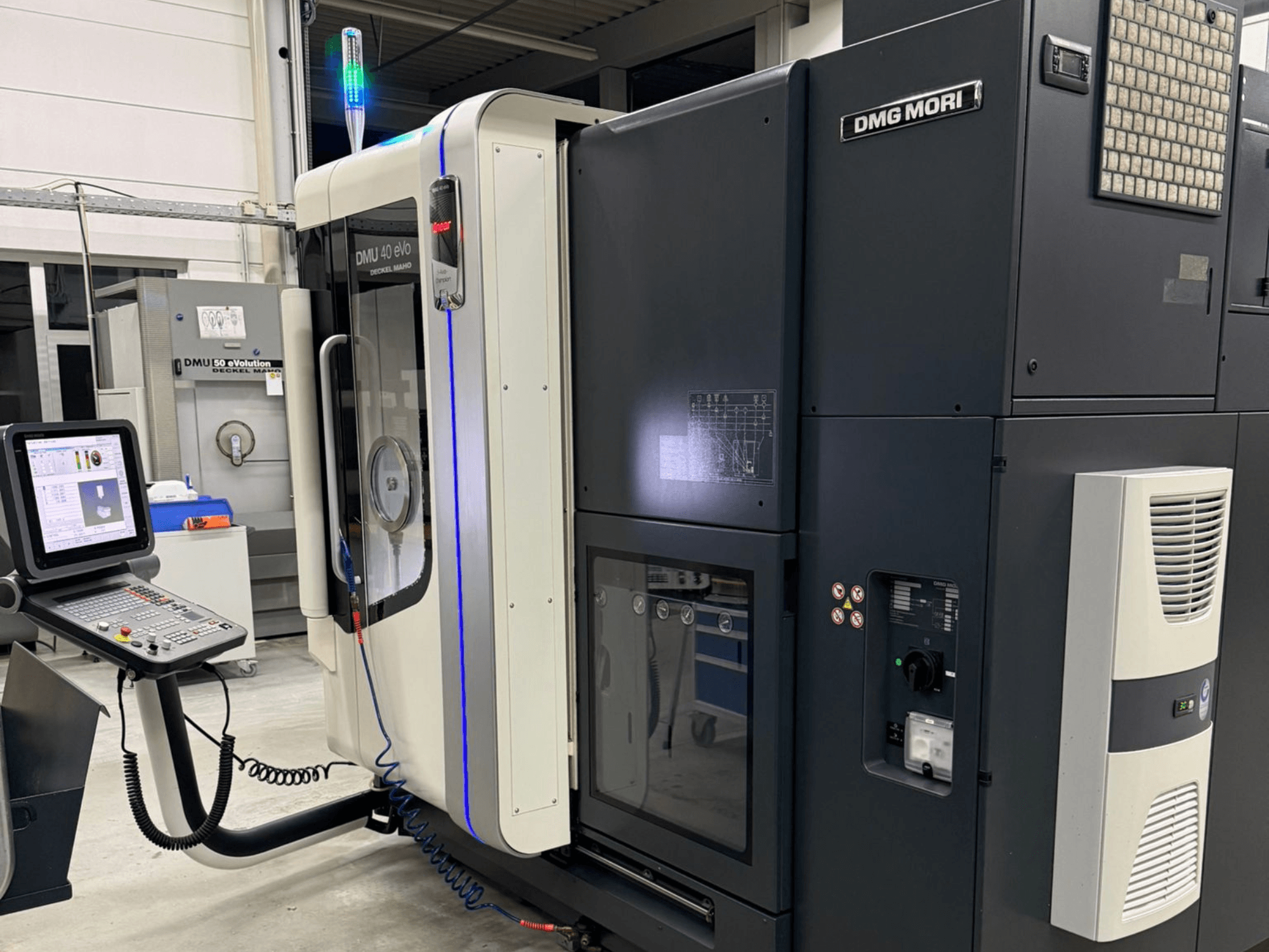DMG MORI DMU 40 eVo masin, esivaade, kus on näha juhtimisseadmed, LED-indikaatorid ja elegantse disainiga masin, mis rõhutab tööstuslikke omadusi.