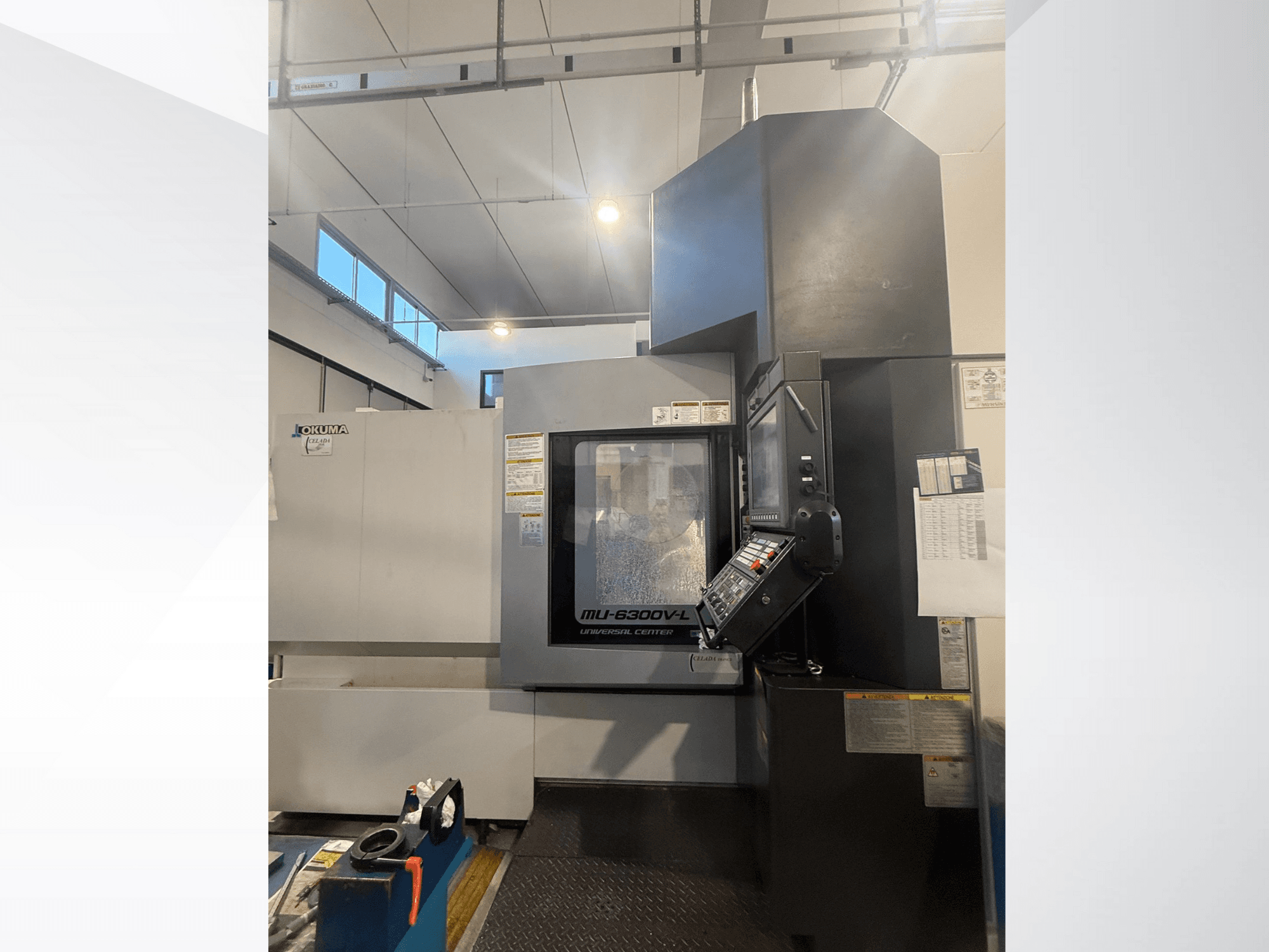 Okuma MU-6300V-L CNC-tööpink ees, kus on näha juhtpaneel ja ohutussildid.