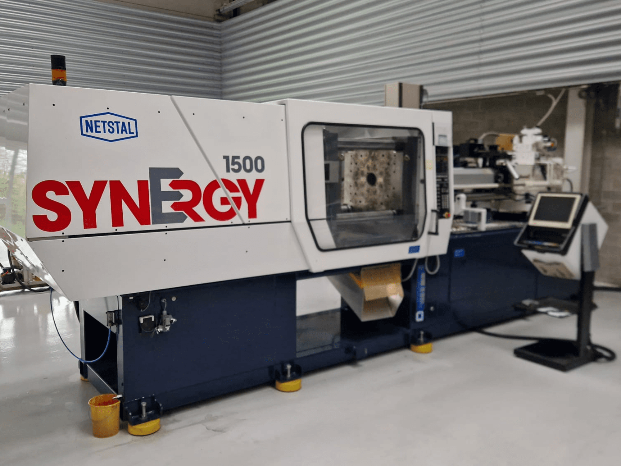 Netstal Synergy 1500-460 hüdrauliline survevalu masin, esiplaanil, kus on näha juhtpaneel ja avatud sissepritseala.