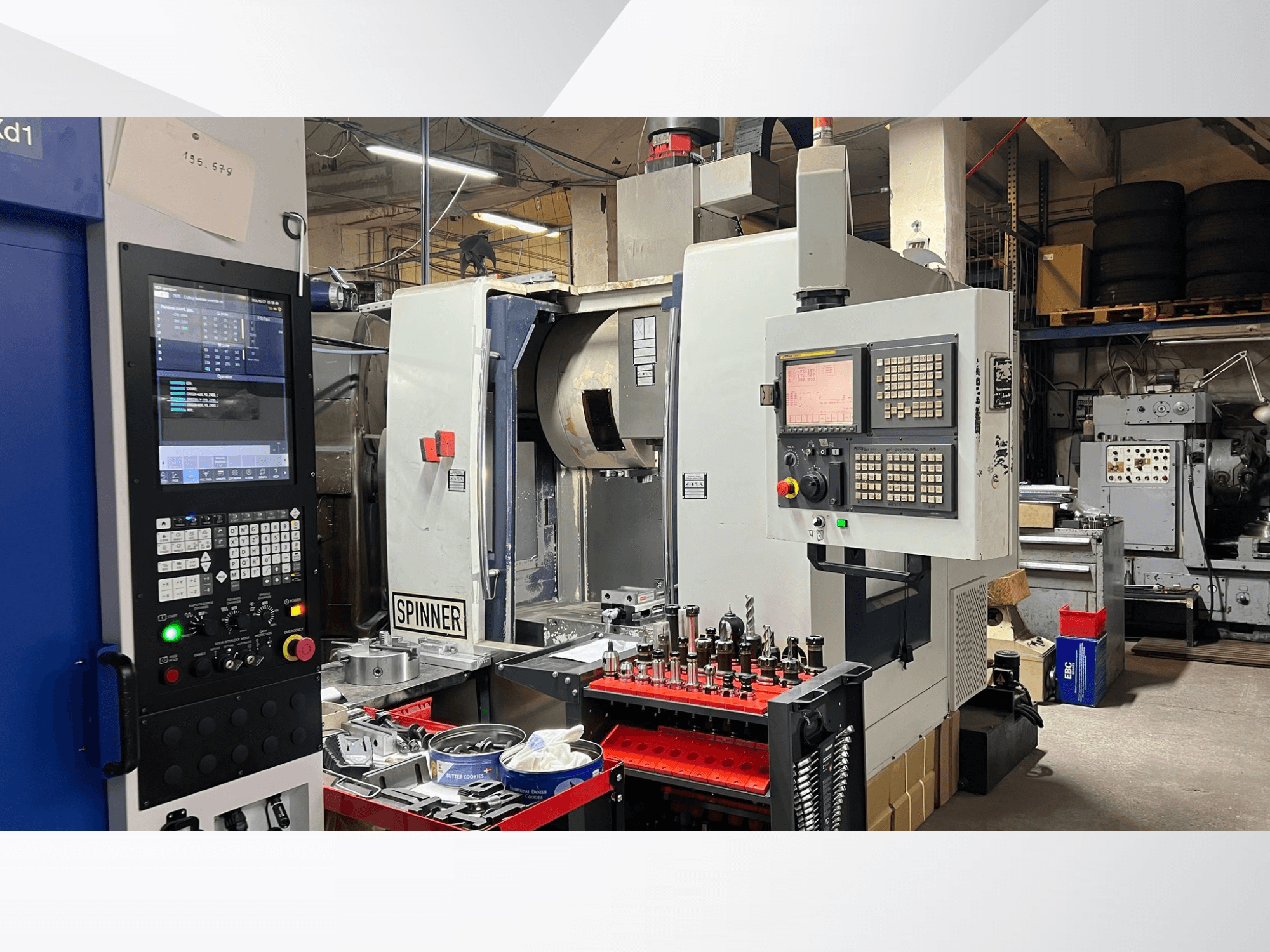 CNC-tööpink, mille juhtpaneel, tööriistad ja töödeldavad detailid on nähtavad, vaadatuna töökojakeskkonnas esiotsast.