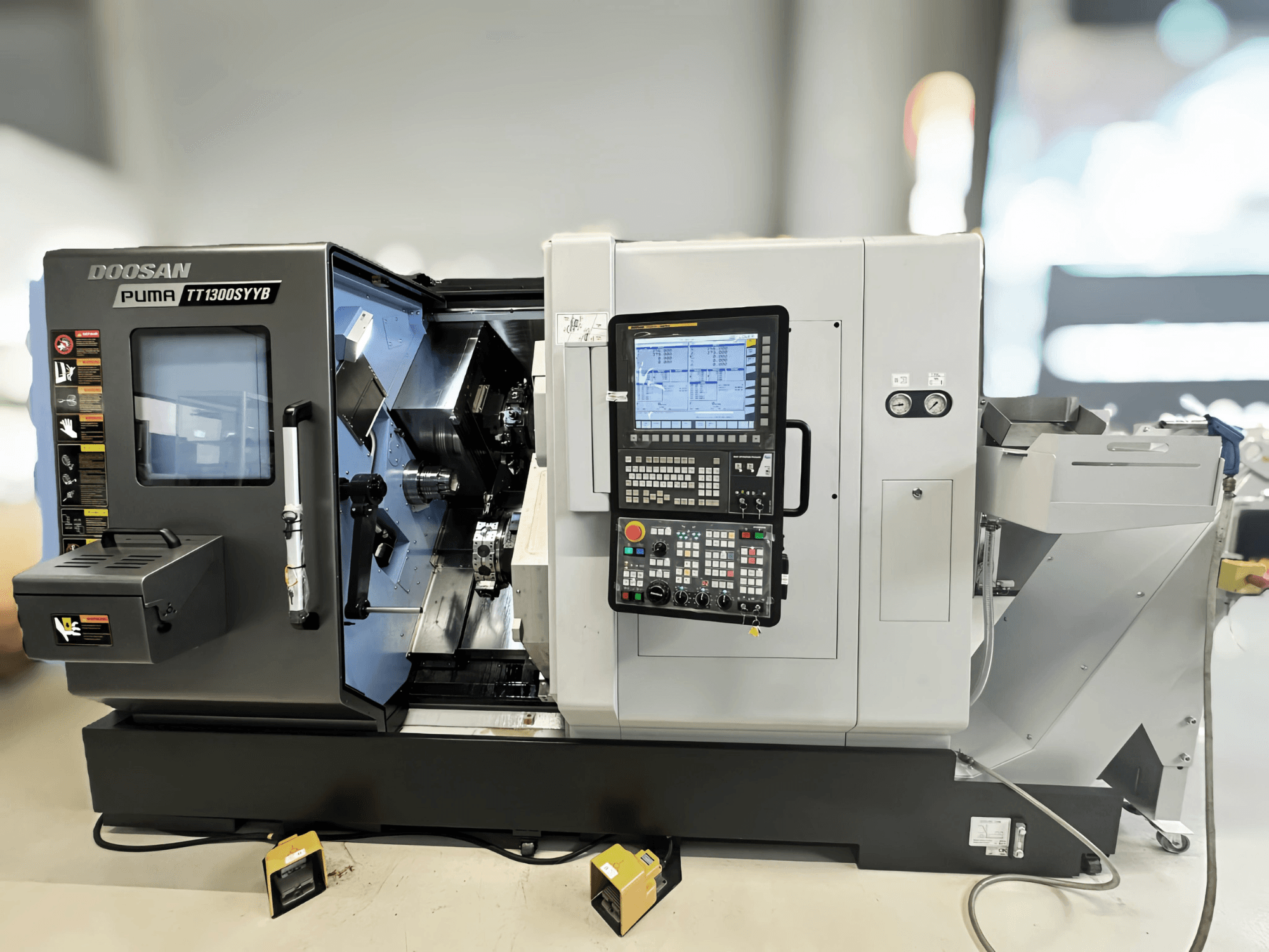 Doosan Puma TT1300SYYB treipingi keskus külgvaates, kus on näha juhtpaneel ja masina sisemus koos tööriistadega.