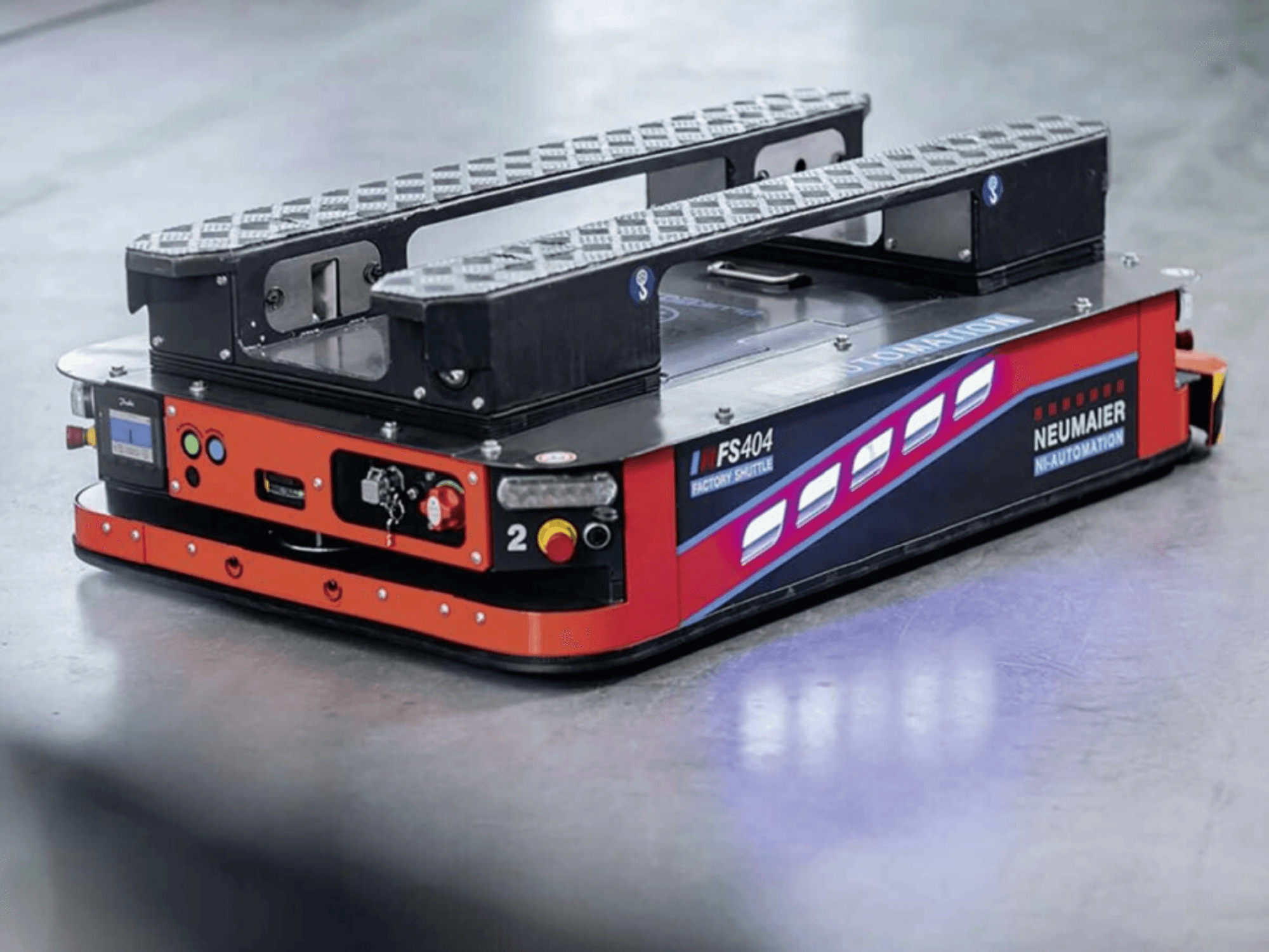 NEUMAIER AGV Factory Shuttle FS404, madala profiiliga kaubaaluste käitlemissüsteem, külgvaade, millel on näha rattad, juhtimisseadmed ja turvaelemendid.