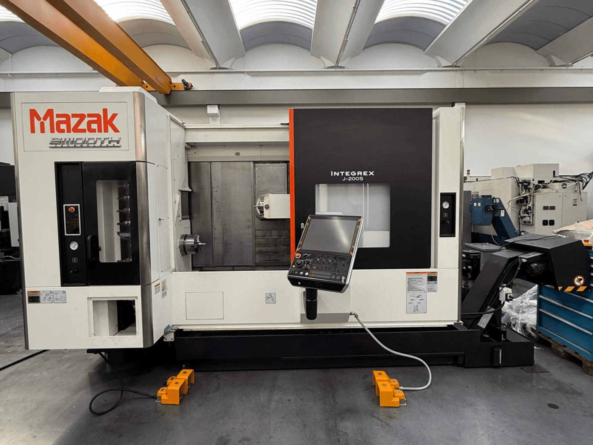 Mazak INTEGREX J-200 S freespinkide keskus esiplaanil, kus on juhtpaneel ja tööpind, tehase põrandal.