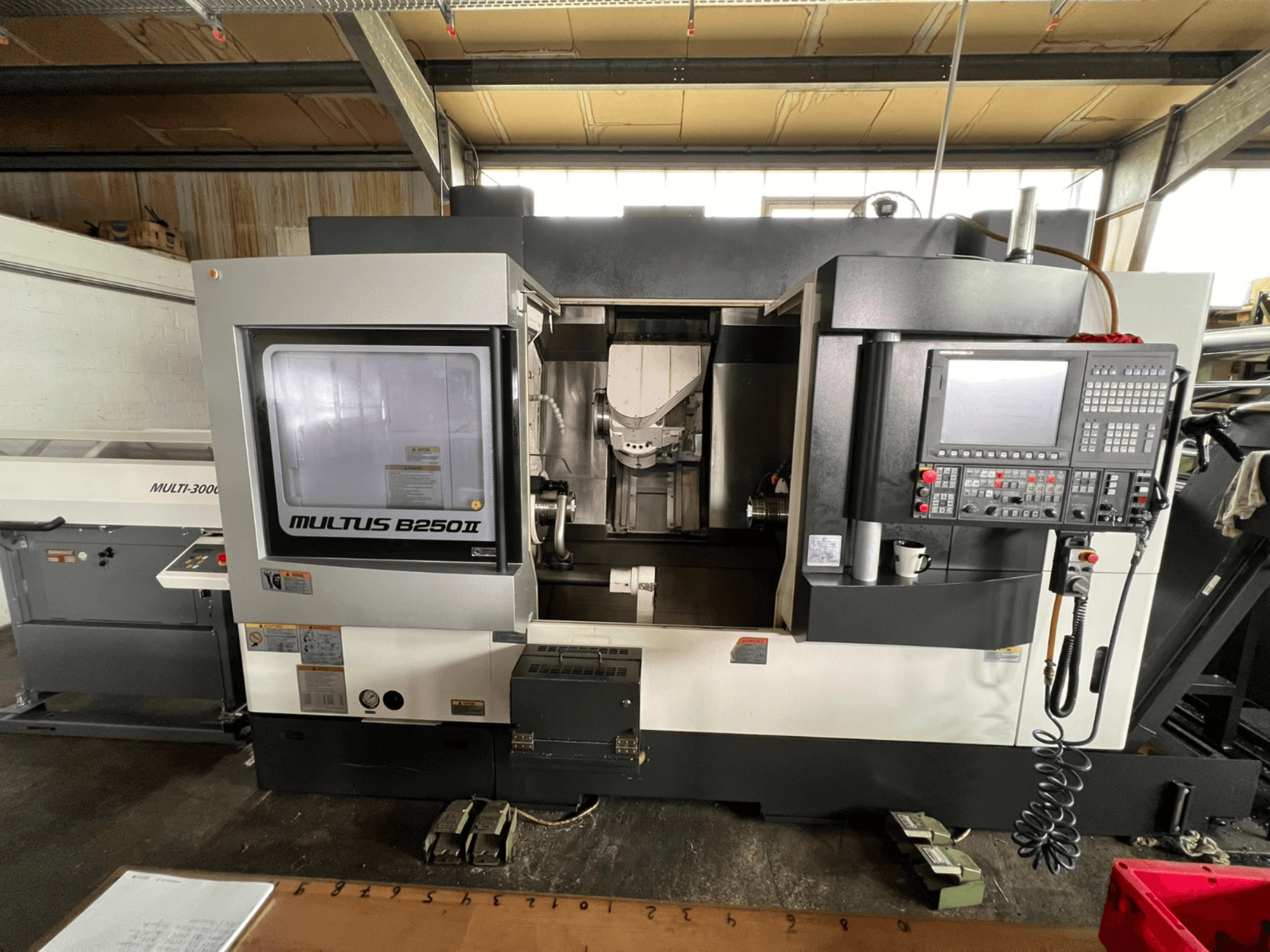 Okuma Multus B250II MW treimis- ja freesimiskeskus, vaade eest, millel on näha juhtpaneeli ja töötlemispiirkonna üksikasjad.