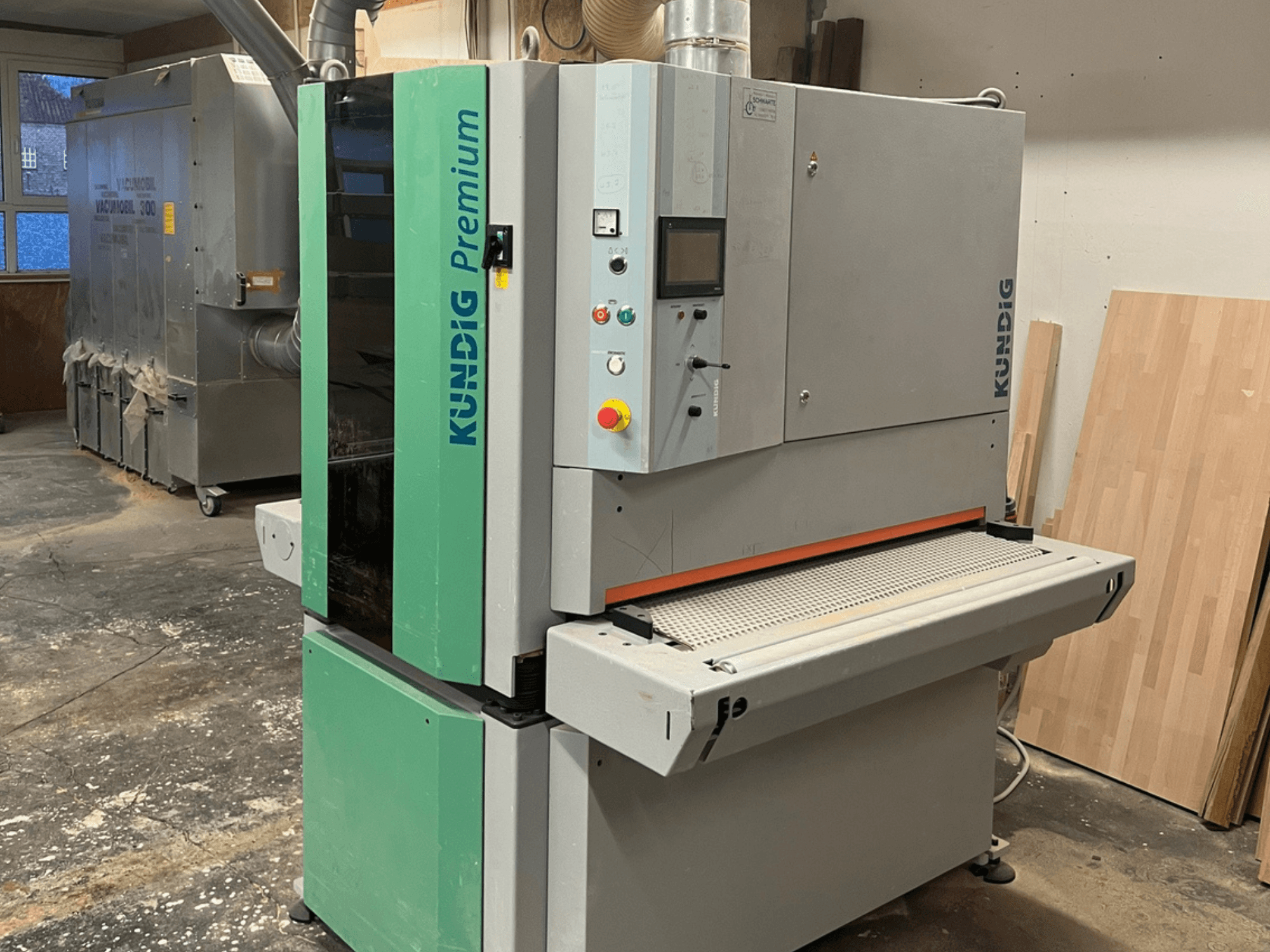 Kundig Premium-1 1100K halli ja rohelise värvi lintlihvijaga, pildil külgvaates, kus on näha juhtpaneel ja lihvimisrihm.