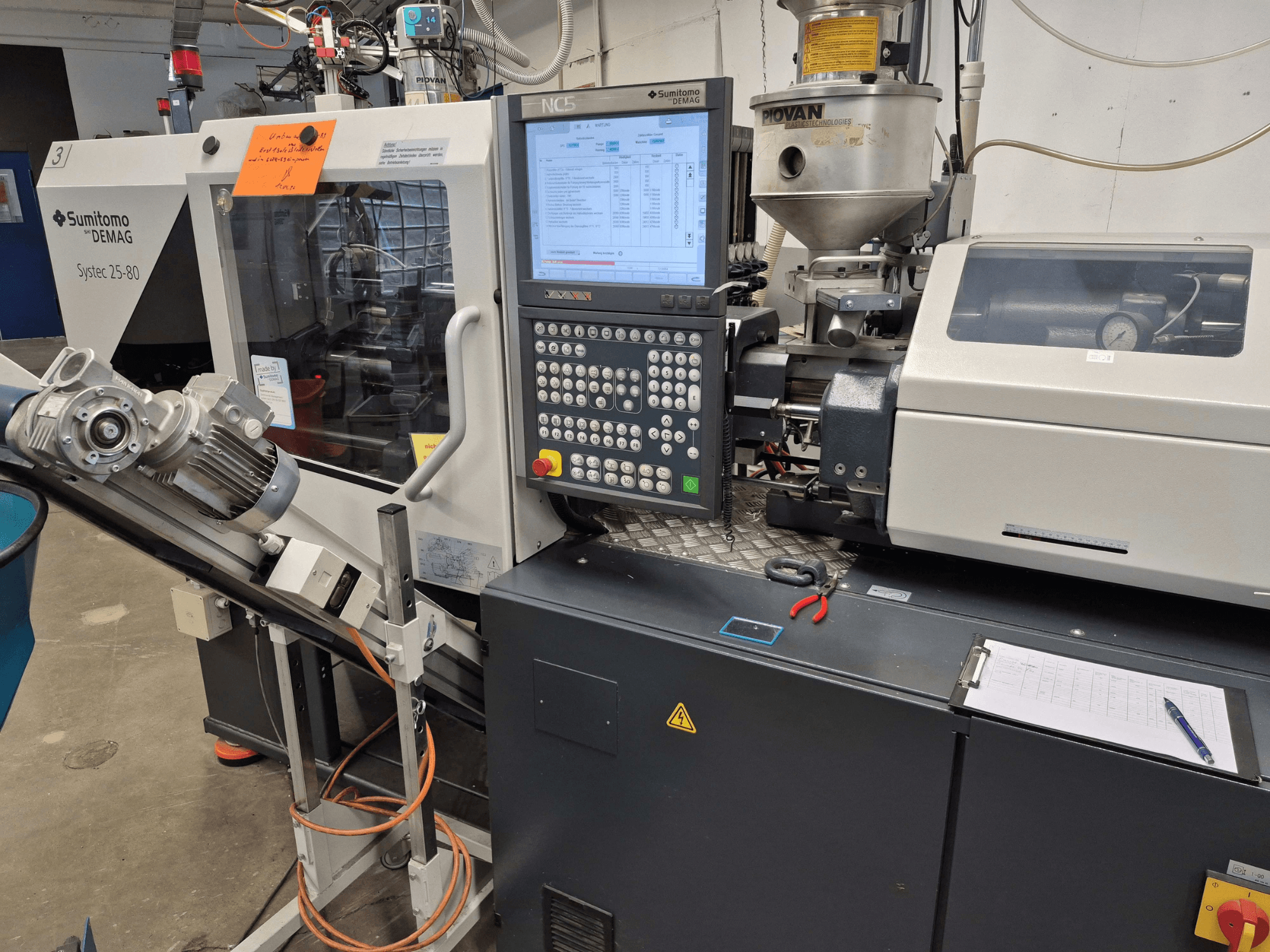 Hüdrauliline survevalumasin SUMITOMO SHI DEMAG Systec 25/320-80, vaade eest, kus on näha juhtpaneel ja materjalitoitesüsteem.