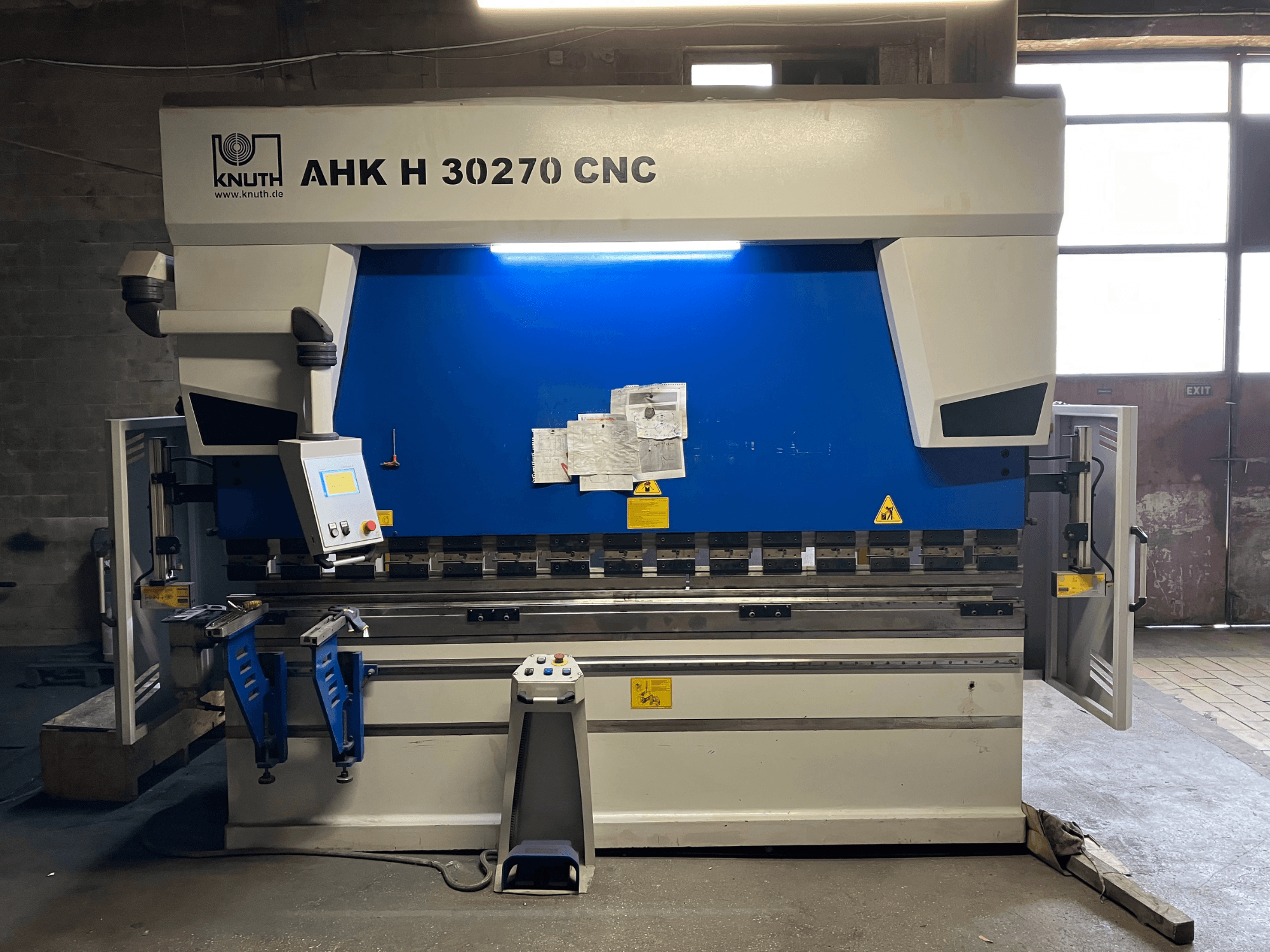 Töökojas asuv KNUTH AHK H 30270 CNC-painutuspress, vaade eest, millel on näha juhtpaneel ja sinine-valge disain, avatud külguks.