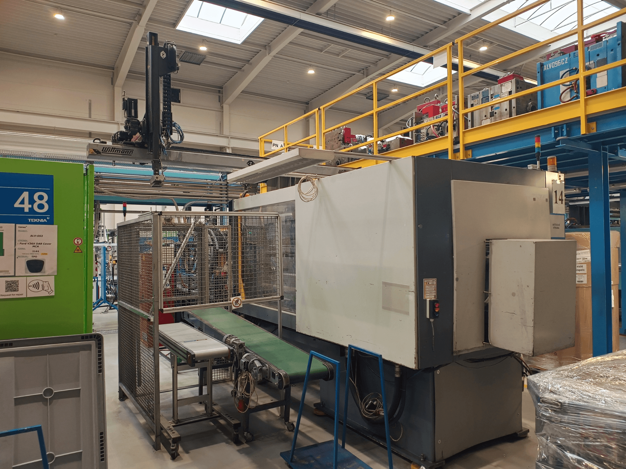 Winmon'i tööstusautomaatika masin, külgvaade, millel on näha konveierilint, juhtpaneel ja turvahäkk tehases.