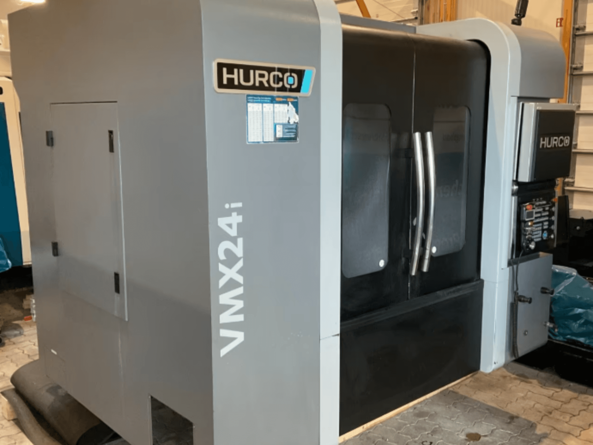 Hurco VMX 24i vertikaalne töötlemiskeskus, vaade eest: metallhall korpus, mustad paneeluksed ja juhtpaneel.