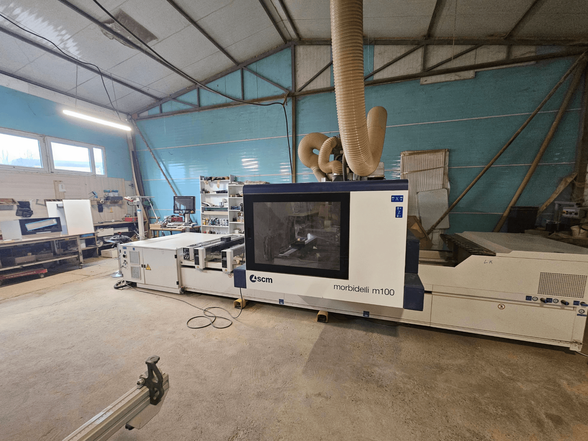 SCM Morbidelli M100 CNC-tööpink töökojas, esivaade, kus on näha tolmueemaldussüsteem ja juhtpaneel.