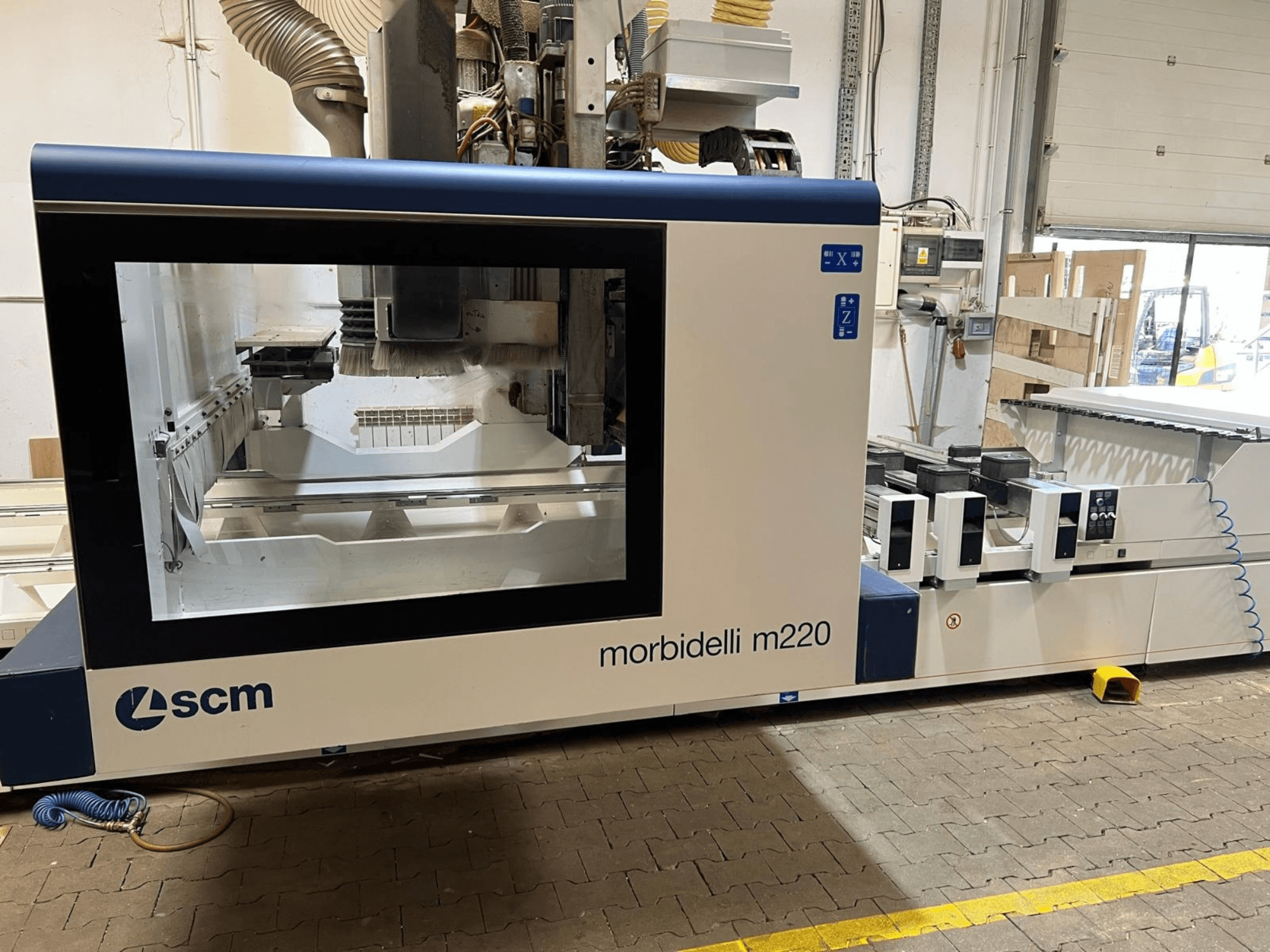 SCM Morbidelli M220 CNC-töötlemiskeskuse esivaade, millel on näha suur aken, juhtpaneel ja töötsoon.
