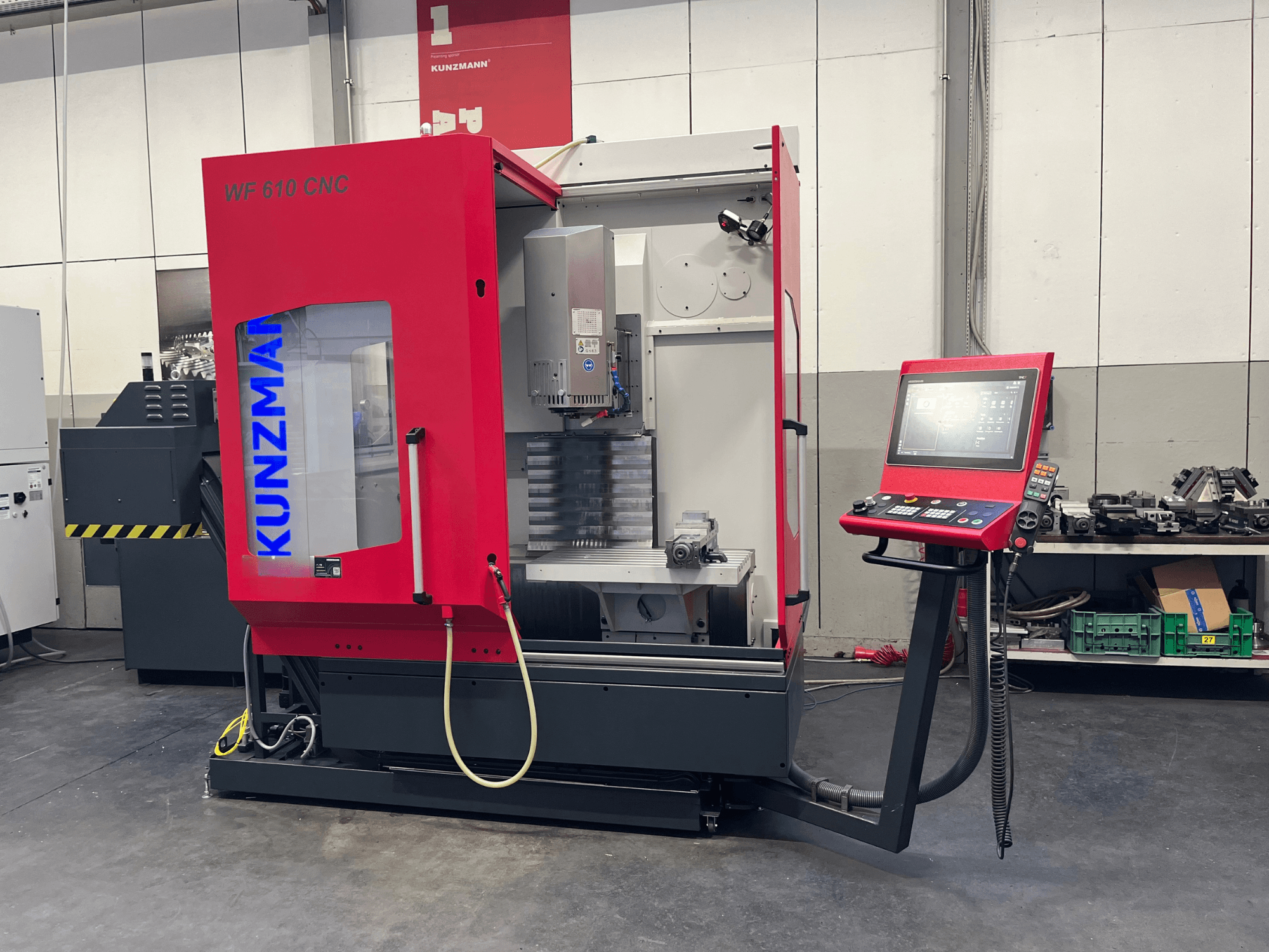 Töökojas asuv KUNZMANN WF 610 CNC vertikaalne töötlemiskeskus, millel on juhtpaneel ja nähtavad masinaosad.