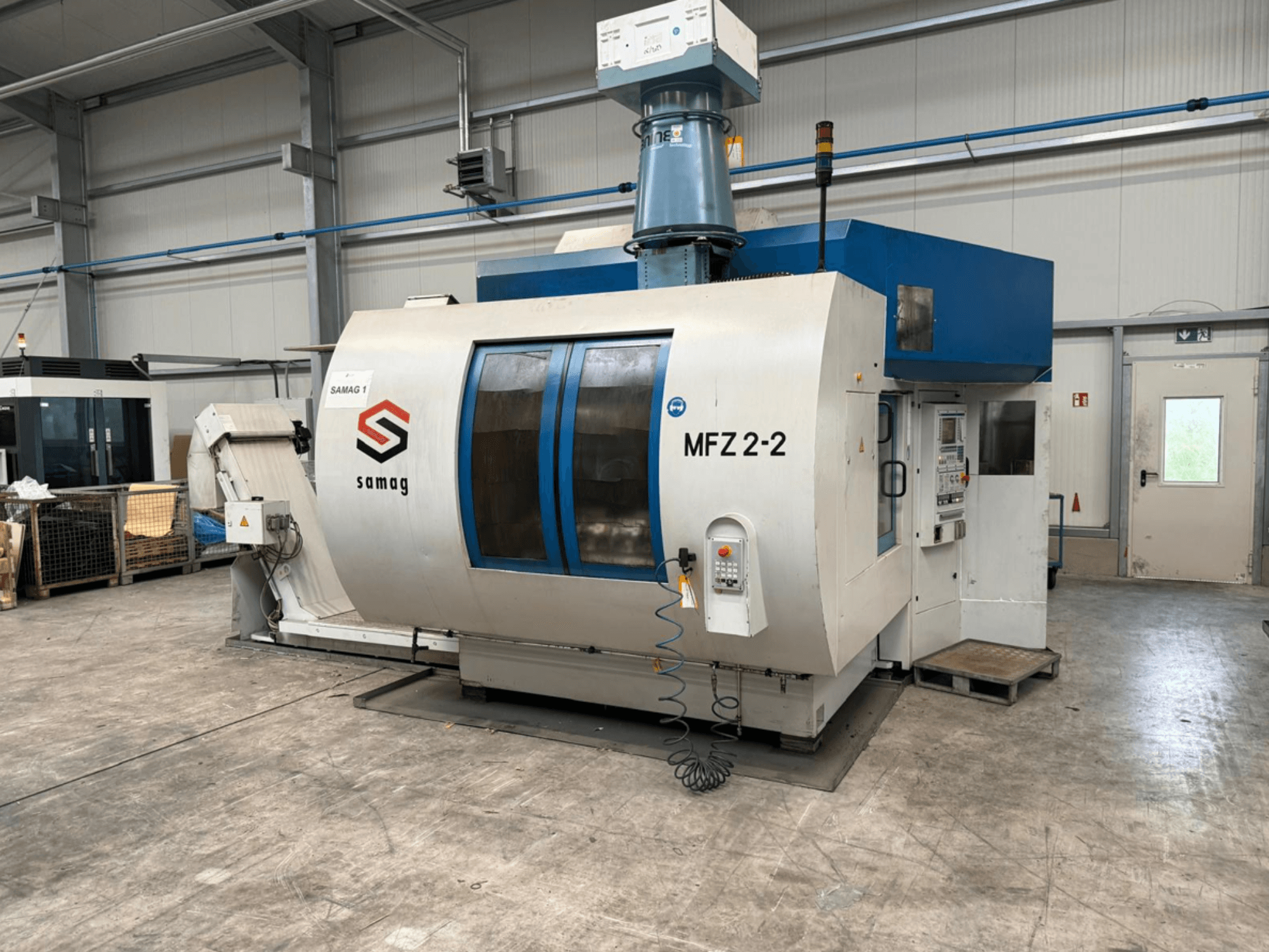 Tööpingi Samag MFZ 2-2, esivaade, kus on näidatud juhtpaneel ja sinine ülemine osa, koos ohutusseadmetega tööstuslikus keskkonnas.