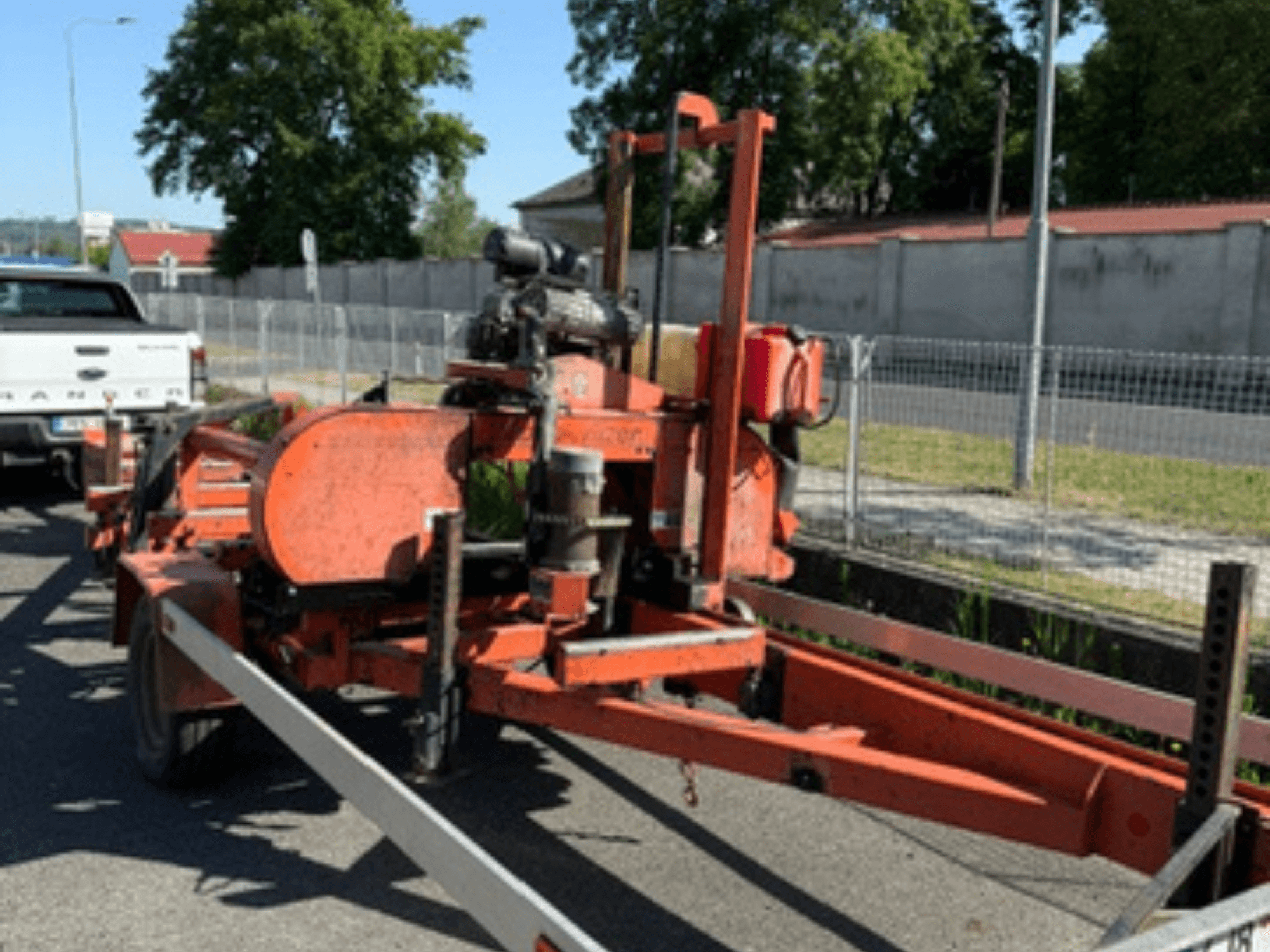 WOOD-MIZER LT40 puidulintsaag oranžis värvitoonis, külgvaade haagisel, millel on näha rattad ja mootori osad.