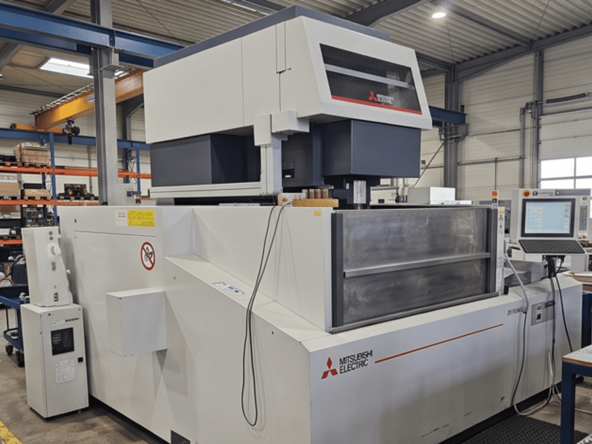 Mitsubishi MV-4800 traat-EDM-masin, vaade eest, millel on näha juhtpaneel ja tööala tehase keskkonnas.