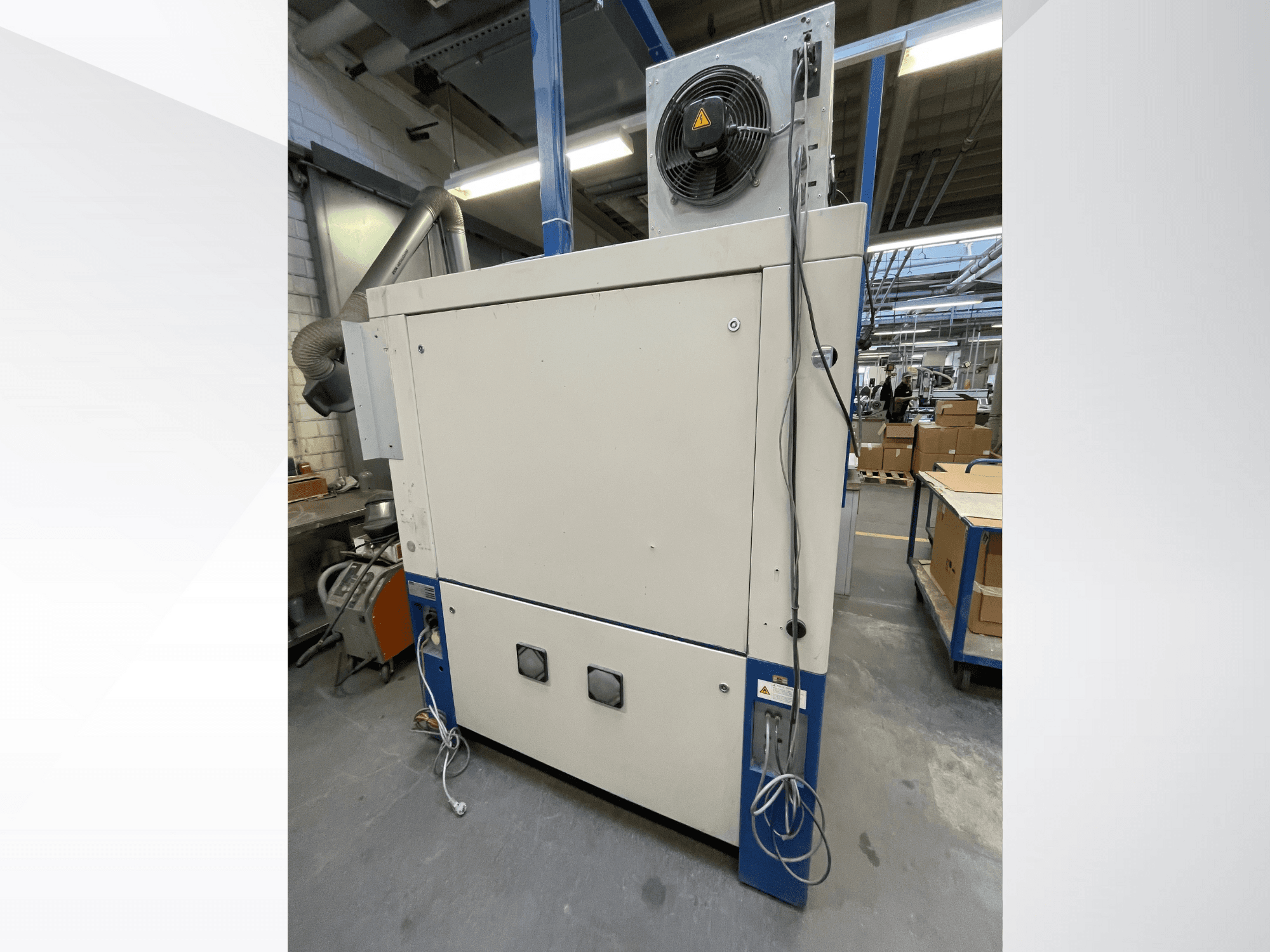 Tööstuslik kuivatusmasin ventilaatoriga, külgvaade; ventilatsiooni ja mitme elektrilise ühendusega. Marki/mudelit ei ole näha.