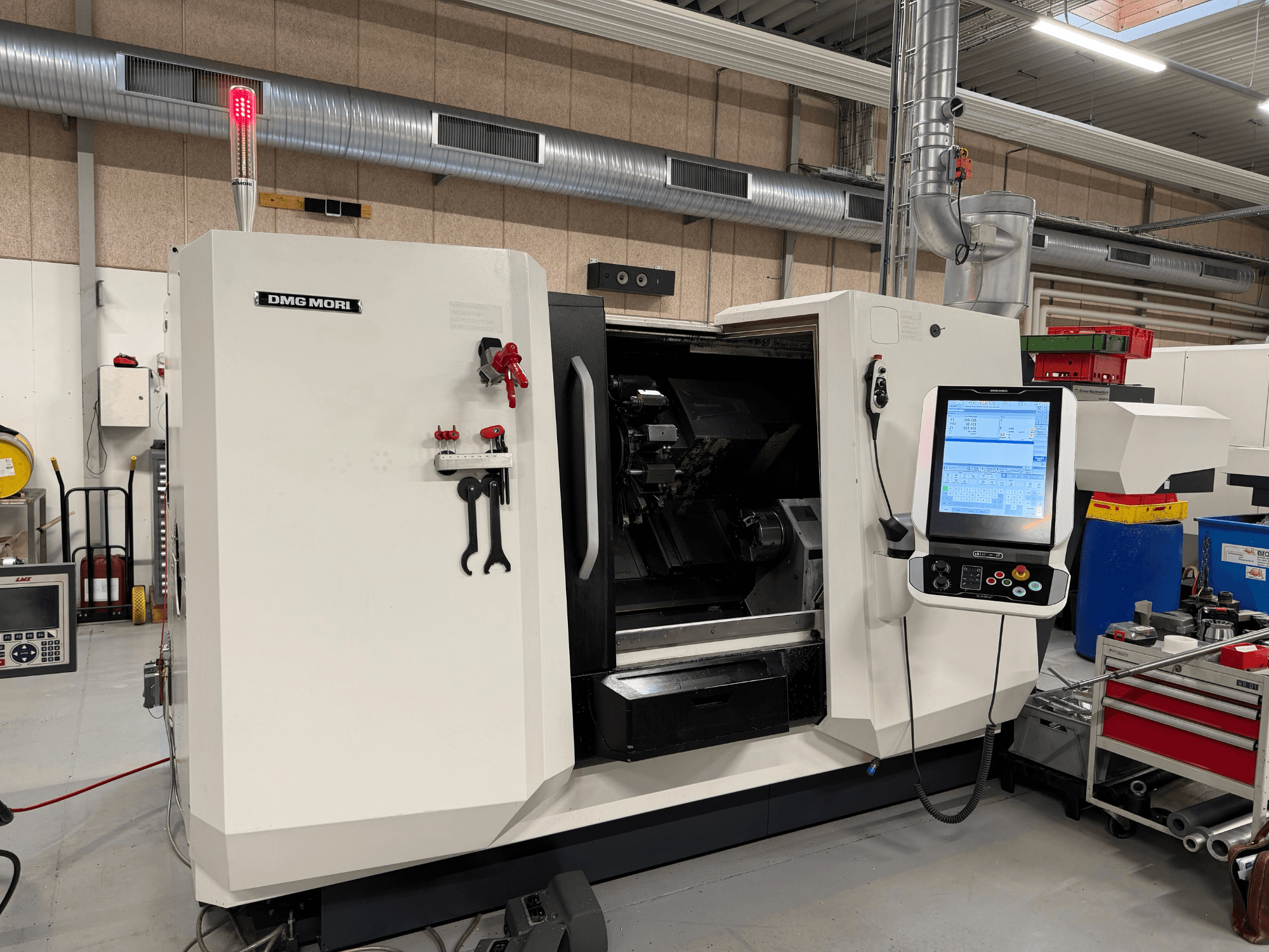 DMG MORI CLX 450 V6 horisontaalne treipink, vaade eest, millel on näha juhtpaneel, hädaseiskamisnupp ja ohutusvalgus.