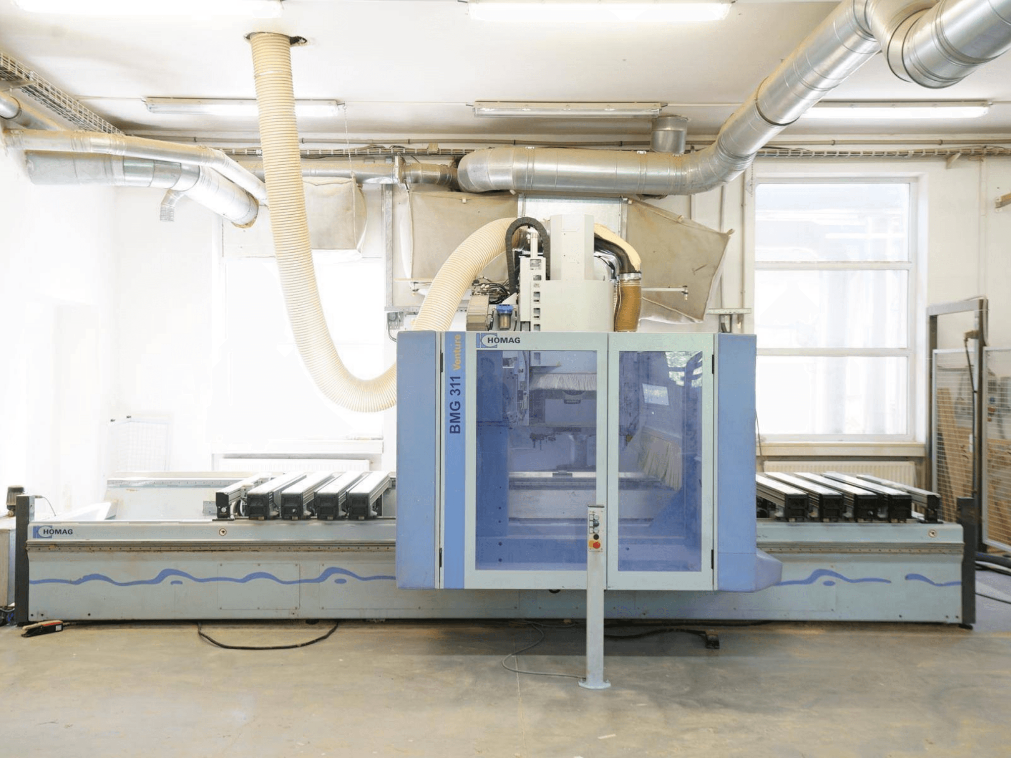 CNC-puidutöötluskeskus HOMAG V BMG 311/42/F/K, vaade eest, millel on suur tööpink ja tolmuimejasüsteem.