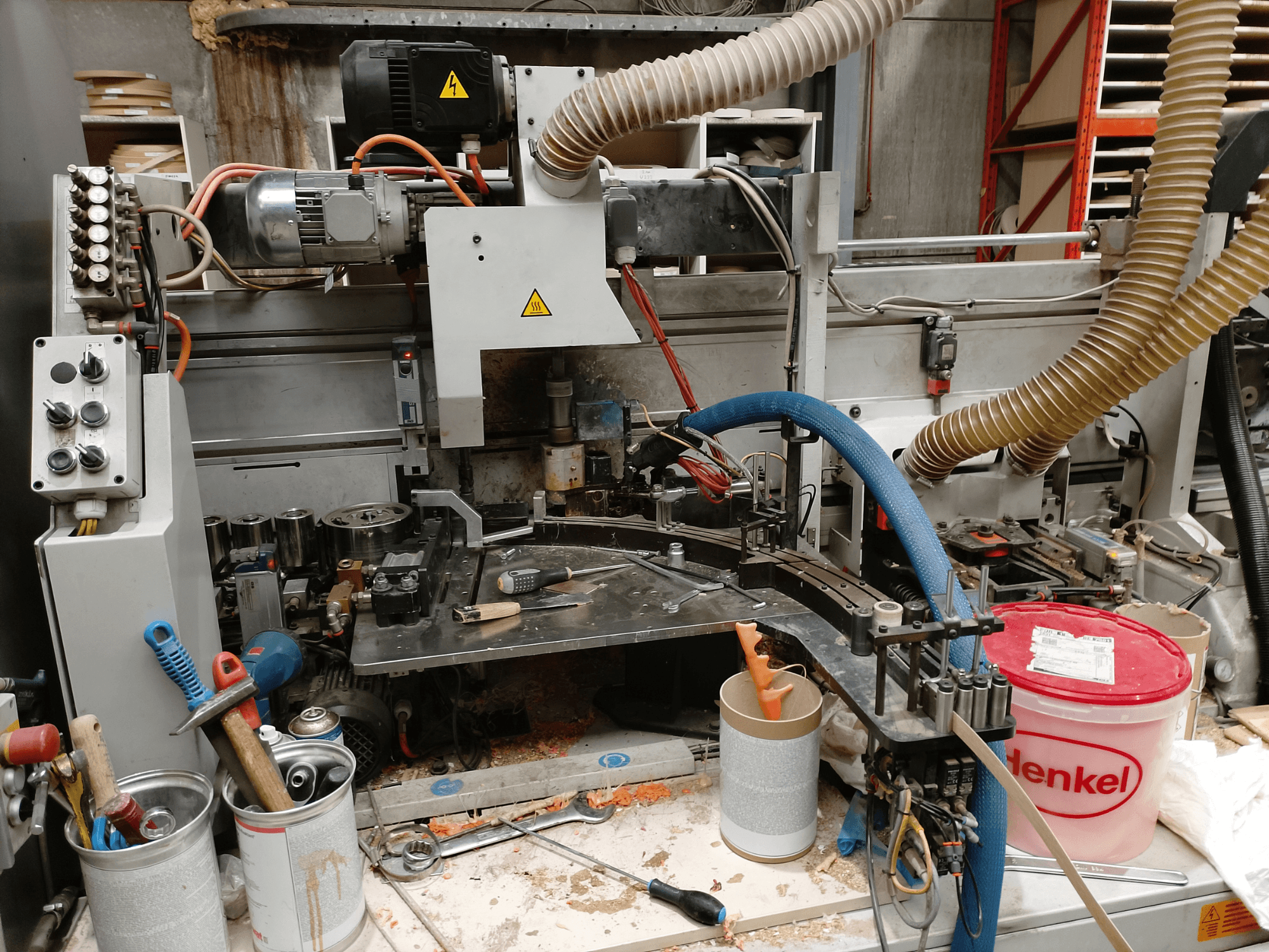 BIESSE Edge Stram B1 servakandur esiplaanil, kus on masinad, voolikud ja töövahendid keset puidulaaste.