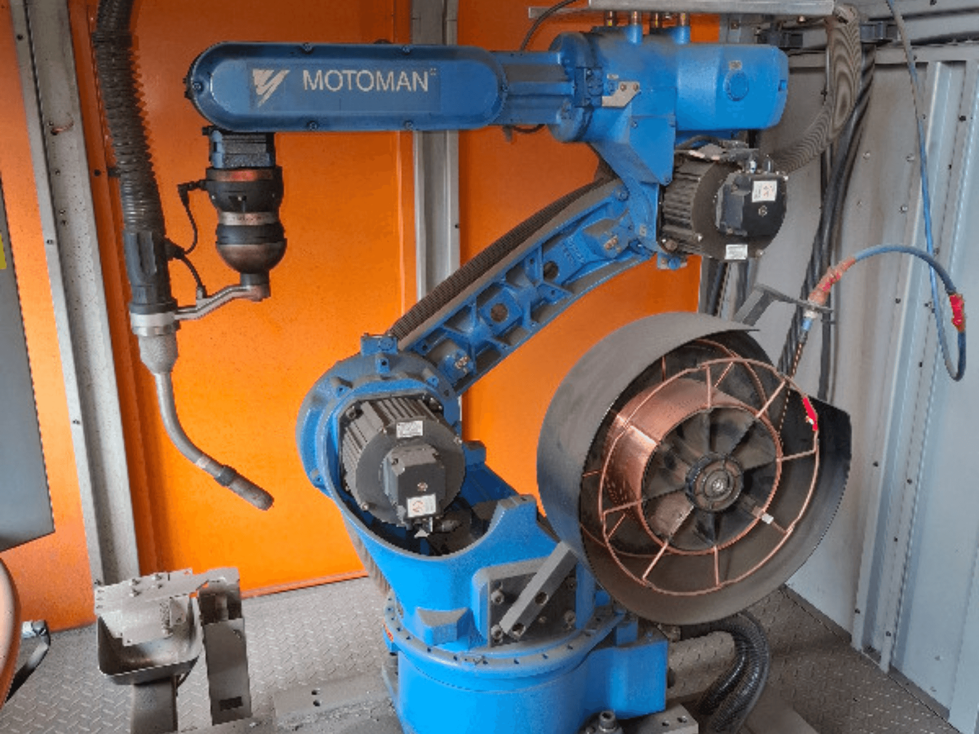 MOTOMANi robotkäsi sinises toonis, külgvaates, kinnitatud ventilaatori ja tööriistadega, näidates mehaanilisi detaile ja ühendusi.