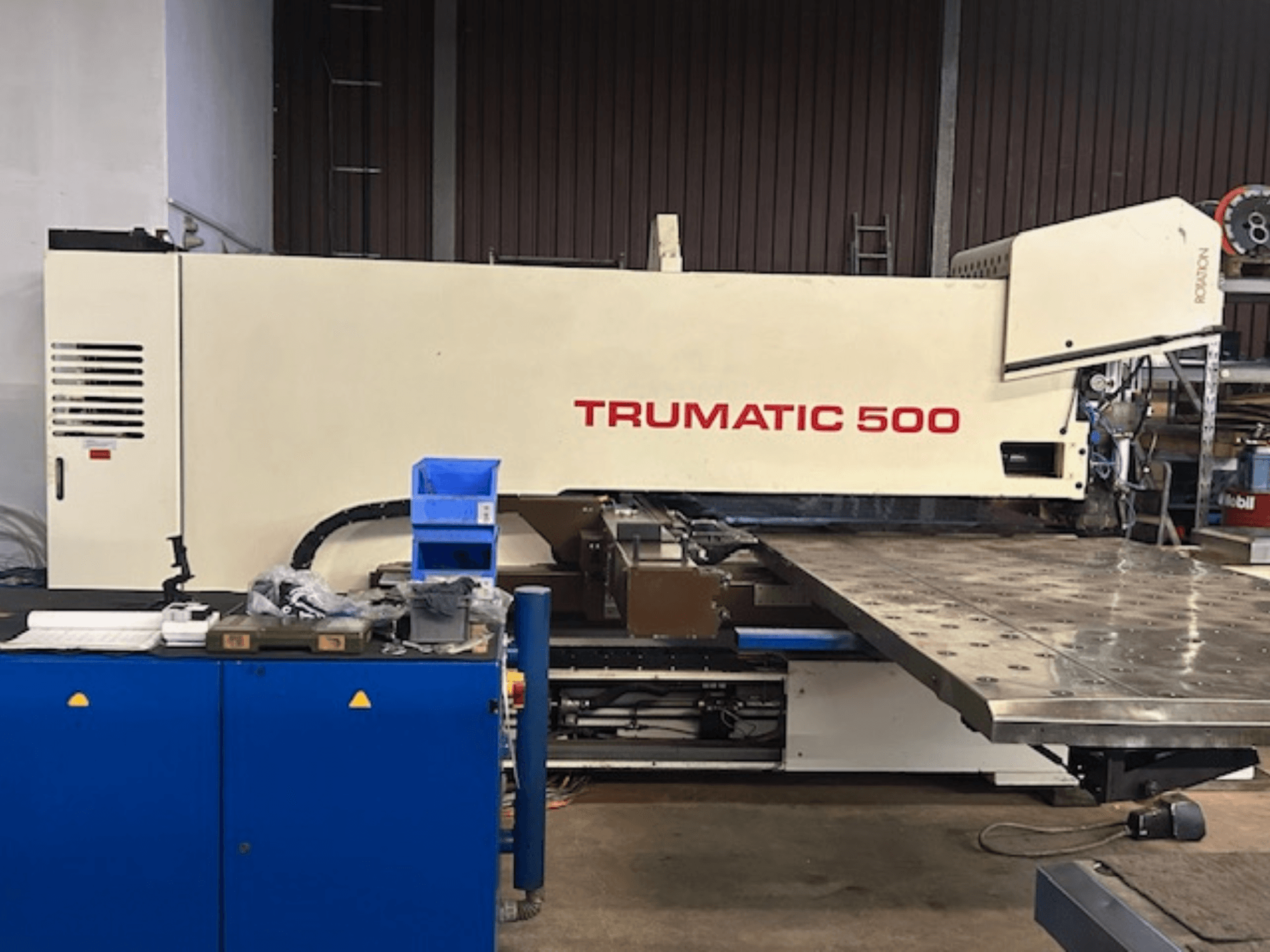 TRUMPF TRUMATIC 500 CNC-stantsimismasin, esiplaanil, juhtpaneel ja suur töölaud, millel on perforeeritud pind.