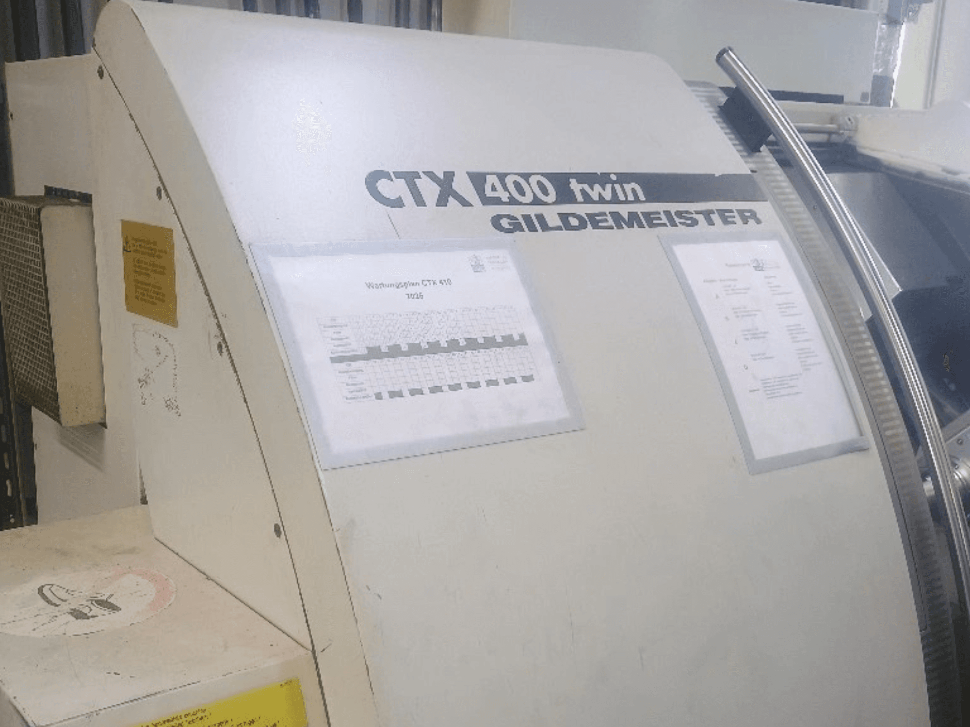 Gildemeister CTX 400 kahe tööpingiga horisontaalne treipink, vaade eest, millel on näha juhtpaneelid ja tehniline dokumentatsioon.