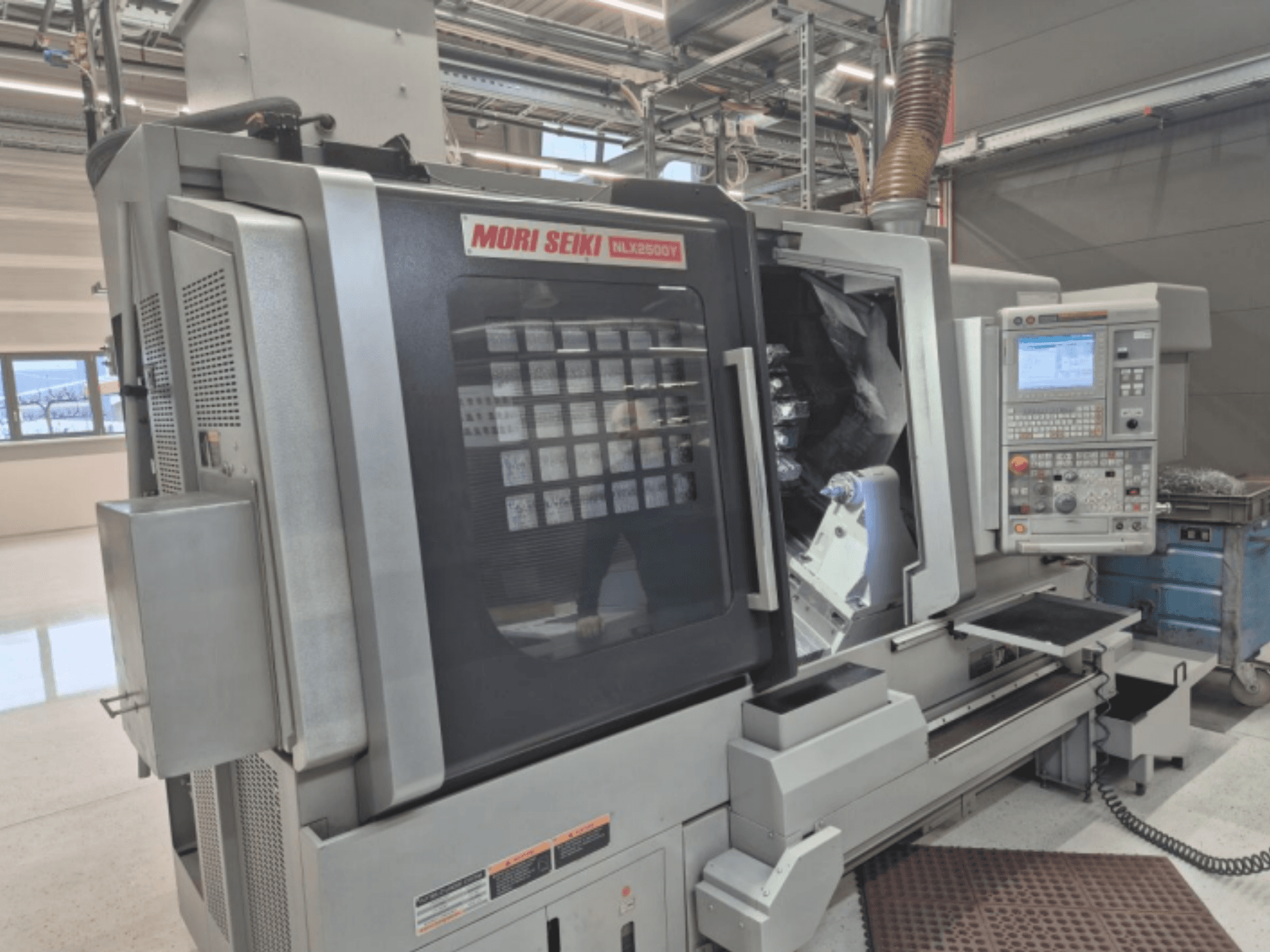 MORI SEIKI NL2500Y CNC-teeninduspingi tehase seadistuses, esiplaanil on näidatud juhtpaneel ja töödeldava detaili kamber.