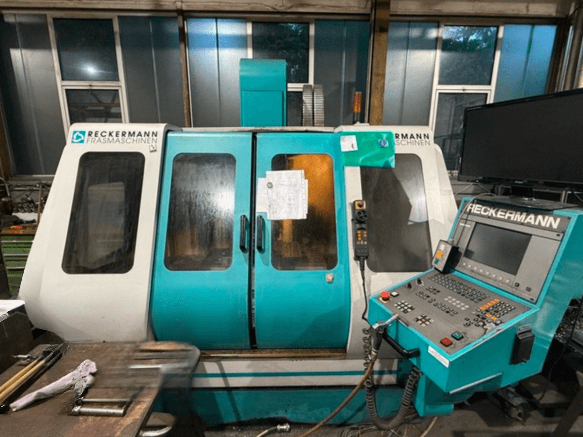 RECKERMANN VMC 850 universaalne töötluskeskus, esiplaanil on juhtpaneel ja klaasuksed.