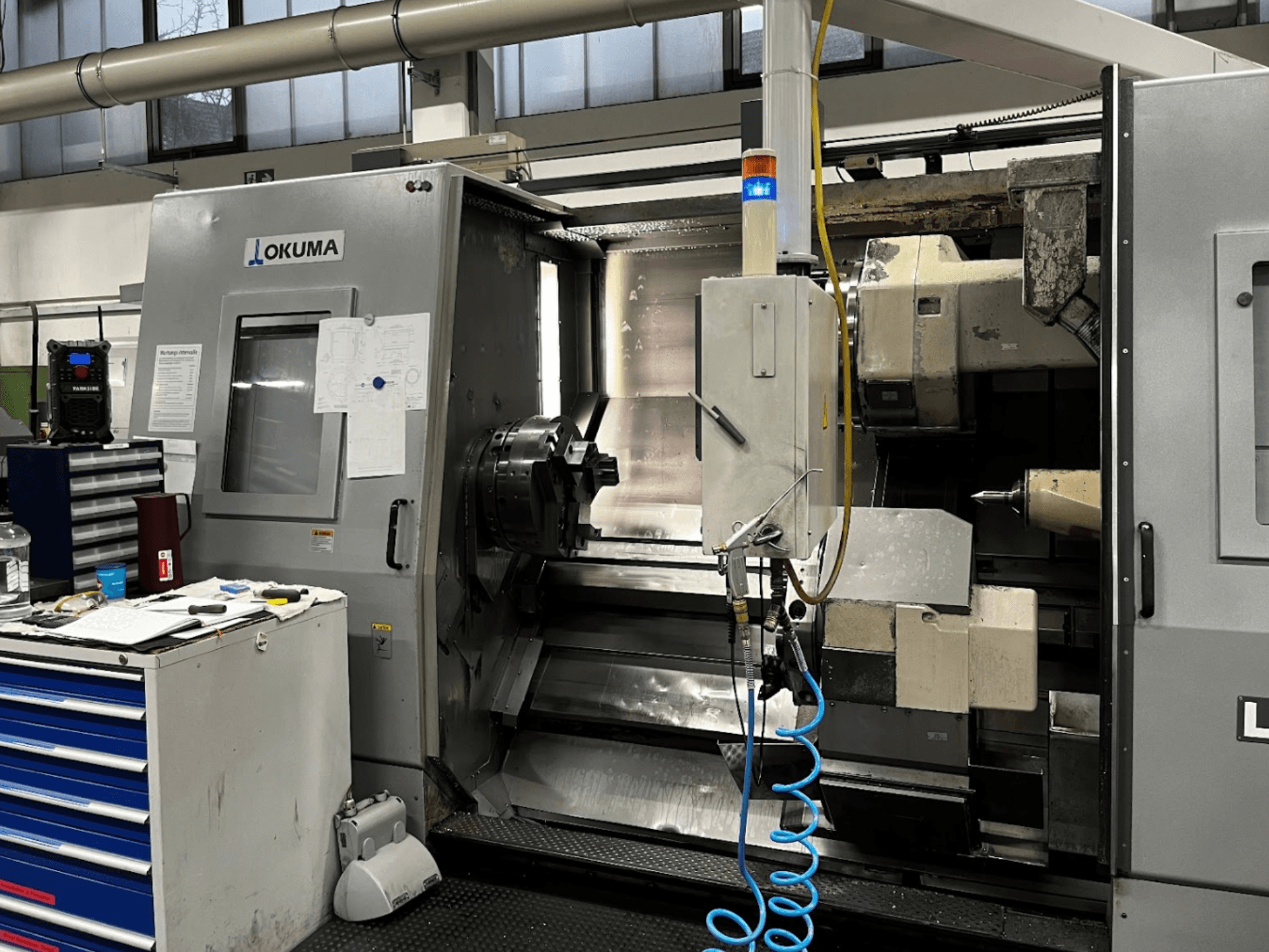 Okuma LU35-M horisontaalne treipink, esiplaanil. Juhtpaneel, tööriistad ja suur taldrik töötlemistoiminguteks.