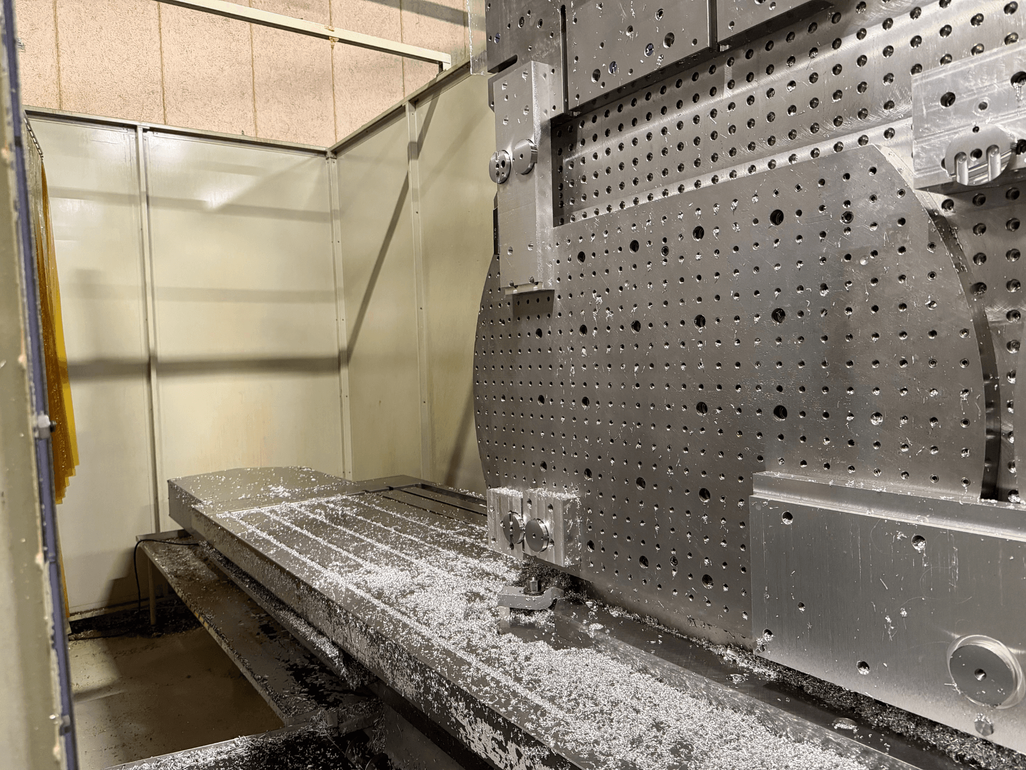 KIHEUNG KNC-U1000 universaalse töötlemiskeskuse esiosa lähivaade, millel on näha metalltöölaud koos alumiiniumilaastudega.