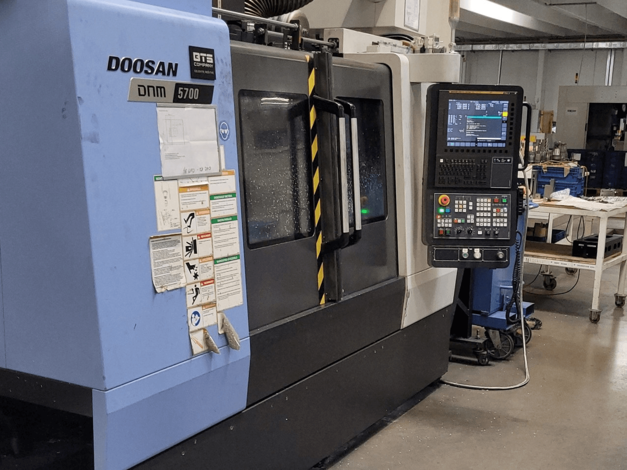 DOOSAN DNM 5700 vertikaalne töötlemiskeskus, vaade eest, millel on näha juhtpaneel ja juhtimisseadmed.
